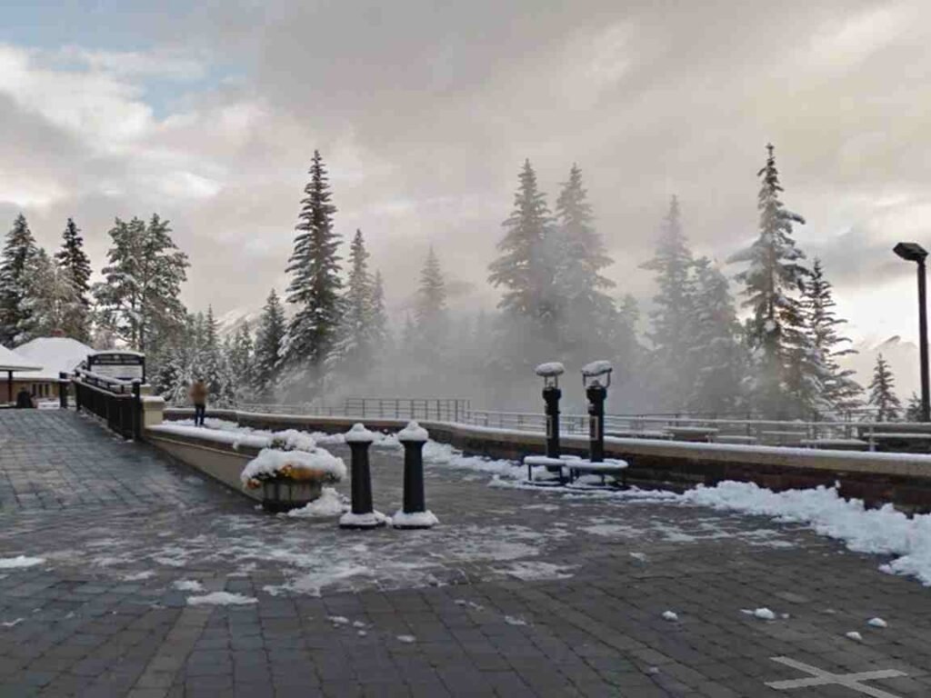 Steam rising from Banff Upper Hot Springs pool with mountain views in winter